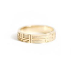 a yellow gold ring with an etched design on the front and side, sitting against a white background