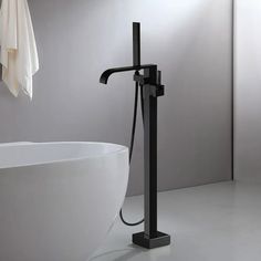 a black faucet sitting next to a white bath tub in a bathroom with gray walls