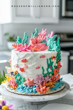 a white cake decorated with colorful sea life and corals on a marble countertop