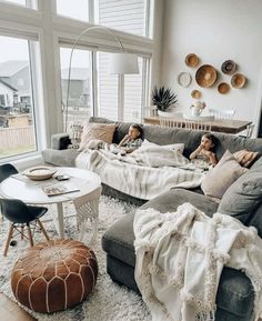 two children are laying on the couches in this living room with white walls and large windows