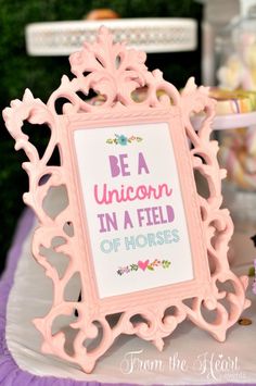 a pink and white sign that says be a unicorn in a field of horses on it