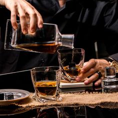 two men are pouring whiskey into glasses on a table