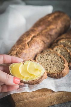 a person holding a piece of bread with butter on it