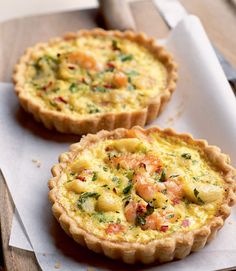 two quiche pies sitting on top of a wooden table