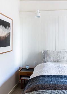 a bedroom with white walls and wood paneling on the headboard is pictured in this image