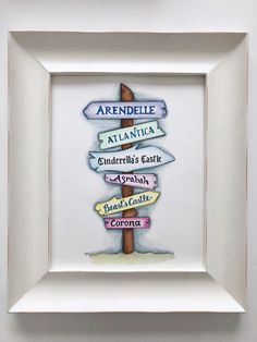 a white frame holding a painting of a signpost with directions to different locations in it