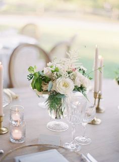 the table is set with candles, flowers and glassware for an elegant wedding reception