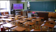 an empty classroom with wooden desks and green chalkboard