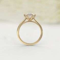 a yellow gold engagement ring with an oval shaped diamond center and two small round diamonds on the side