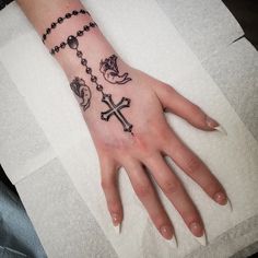 a woman's hand with a rosary and cross tattoo on the middle of it