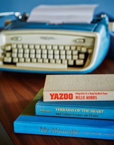 three books stacked on top of each other next to an old typewriter and keyboard