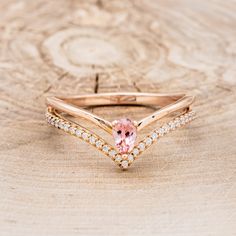 a close up of a ring on a wooden surface with a pink stone in the middle