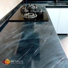 a black counter top in a kitchen next to a stove and oven with two burners