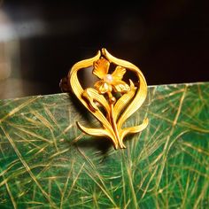 An ethereal art nouveau 14k yellow gold seed pearl accent flower pin from the Victorian era. Featuring a line engraved gold flower with a pearl seed pistil and whimsical leaves that frame the petaled flower. It looks as if one of the gold petals has broken off, unfortunately, but it doesn't seem to affect the overall look of the piece. The brooch has a horizontal brooch pin with a 19th c-clasp. The back of the pin is marked 14k and the gold has been tested for authenticity. In great vintage cond Art Nouveau Gold Flower Jewelry, Art Nouveau Yellow Gold Brooches Gift, Art Nouveau Yellow Gold Collectible Brooches, Gold Art Nouveau Brooches For Gift, Art Nouveau Gold Brooches As Gift, Art Nouveau Filigree Brooch For Collectors, Collectible Art Nouveau Filigree Brooches, Gold Art Nouveau Brooch For Collectors, Art Nouveau Yellow Gold Brooch Jewelry