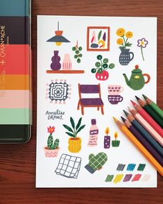 a notebook with colored pencils next to it on a wooden table and a book