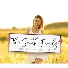 a woman holding a sign that says the smith family in front of a wheat field