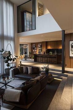 a living room filled with furniture next to a tall glass wall covered in lots of windows