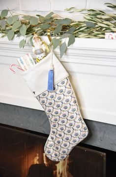 a stocking hanging from a mantel decorated with greenery