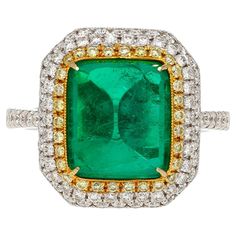 an emerald and diamond ring with two rows of diamonds around the band, set in 18k yellow gold