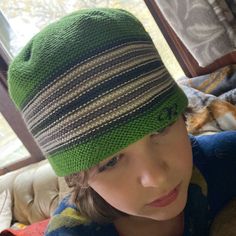 a young boy wearing a green knitted hat