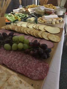 an assortment of cheeses, crackers, and meats on a buffet table