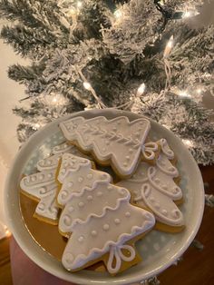 decorated cookies on a plate in front of a christmas tree