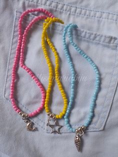 four different colored beads and charms on a pair of blue jeans pocketed in front of a white t - shirt