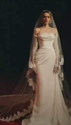 a woman in a wedding dress with a long veil on her head and one arm over her shoulder