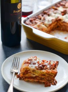 lasagna casserole on a plate next to a bottle of wine