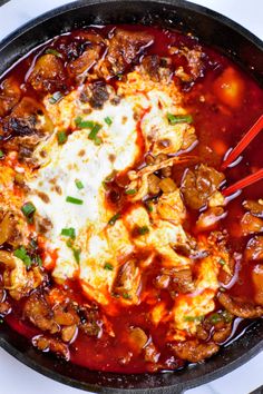 a skillet filled with meat and vegetables covered in sauce