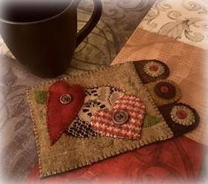 a coffee cup holder with buttons on it and a mug in the middle, sitting next to a quilted coaster