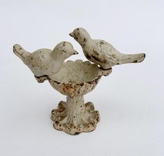 two white birds sitting on top of a bowl