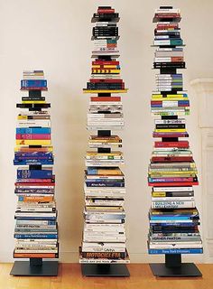 three tall stacks of books sitting on top of each other in front of a fireplace