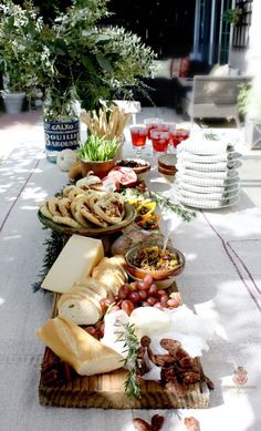 a table topped with lots of food on top of a white tablecloth covered ground