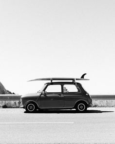 a small car with a surfboard on top of it's roof