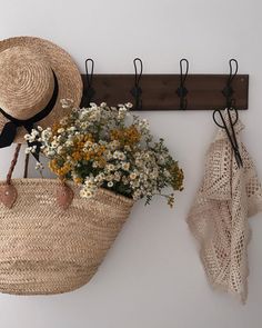 a hat and flowers are hanging on the wall next to a coat rack with hooks