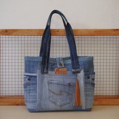 a purse made out of old jeans with a tassel on the front and side pocket