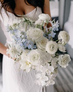 a woman holding a bouquet of white and blue flowers