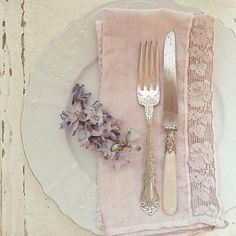 a white plate topped with silverware next to purple flowers on top of a table