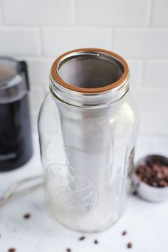 a glass jar filled with coffee beans next to a grinder