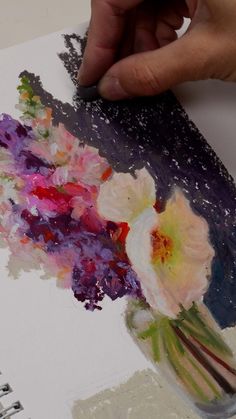 a person is painting flowers in a vase