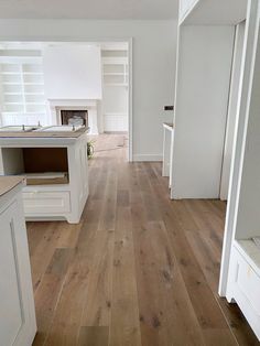 an empty kitchen with wood floors and white cabinets in the background, is shown from the doorway