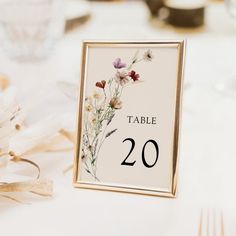 the table numbers are displayed in gold frames with wildflowers on them and ribbons