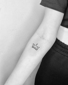 a black and white photo of a woman's arm with a crown tattoo on it