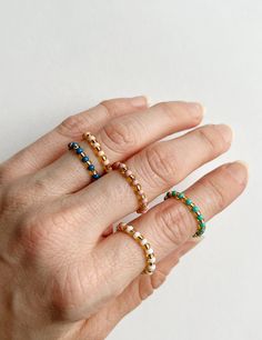 a woman's hand with three different rings on her fingers and one is holding the other