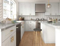 a kitchen with white cabinets and marble counter tops, an island in the middle is surrounded by gold accents