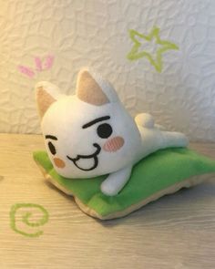 a small stuffed animal sitting on top of a green pillow next to a white wall