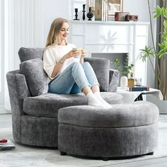 a woman sitting in a chair with her feet up on the ottoman and holding a cup