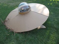 an unusual table made out of cardboard with a glass dome on top sitting in the grass