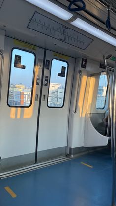 the inside of a subway car with its doors open and some windows showing city buildings